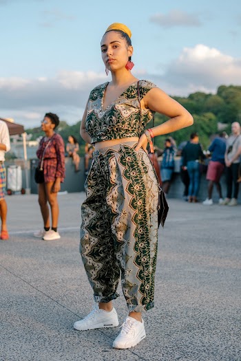 Photo of Posing Woman Standing Akimbo with a Crowd of People in the Background