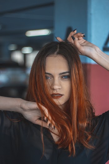 Photo of Posing Woman Wearing Black Top With Hands Above and Under Her Face