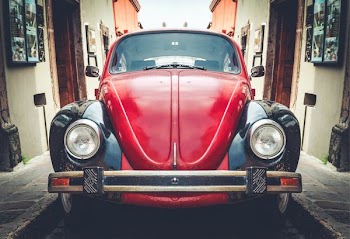 photo of red and black Volkswagen Beetle in alley