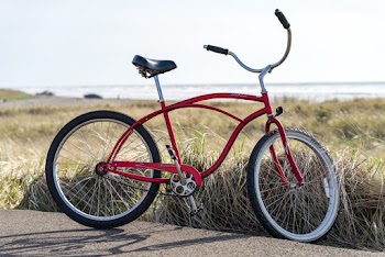 Photo of Red Bike Parked on Road Beside Grass Field