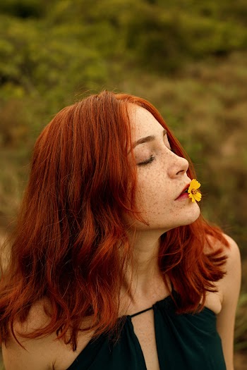Photo of Red-haired Woman With Yellow Petaled Flower on Her Lips