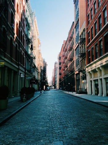 photo of road between brown buildings