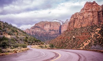 photo of road between brown rocky mountains during daytime