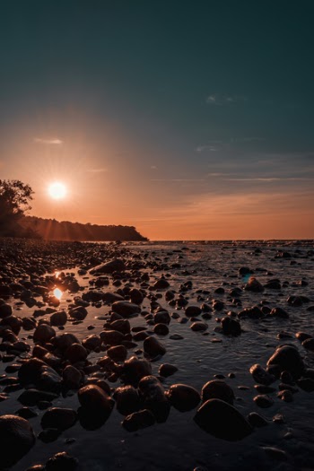 Photo Of Rock Rubles Beside Calm Body Of Water during Golden Hour
