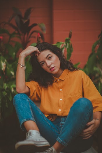 Photo of Sitting Woman in Mustard Shirt and Blue Denim Jeans Posing