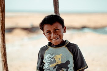 Photo of Smiling Boy Leaning on Wooden Pole