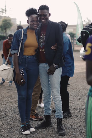 Photo of Smiling Couple Posing Together With People in the Background