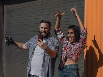 Photo of Smiling Man Holding a Camera Taking a Selfie With a Female Friend