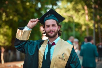 Photo of Smiling Man in Gold and Black Academic Dress Posing