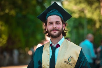 Photo of Smiling Man in Gold and Black Academic Dress Posing