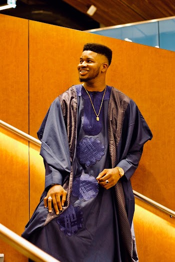 Photo of Smiling Man in Traditional African Wear Standing on Staircase While Looking Away