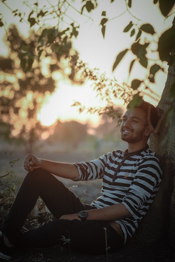 Photo of Smiling Man Leaning on Tree Trunk