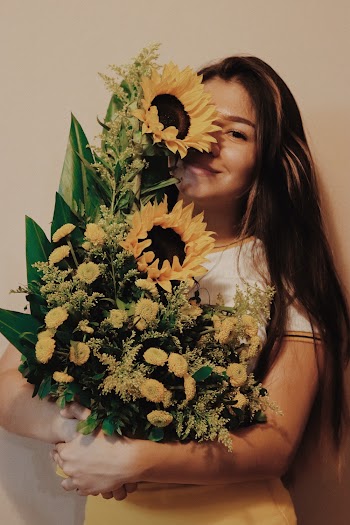 Photo of Smiling Woman Carrying Sunflower Arrangement