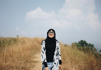 Photo of Smiling Woman in Black Hijab Standing in the Middle of a Dirt Road