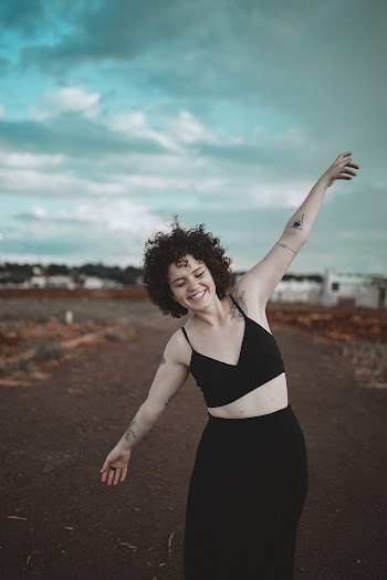 Photo of Smiling Woman in Black Outfit With Her Hands Raised