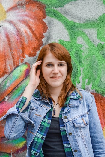 Photo of Smiling Woman in Blue Denim Jacket Standing In Front of Painted Wall