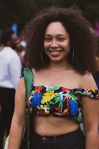Photo of Smiling Woman in Floral Crop Top Posing with a Crowd of People in the Background