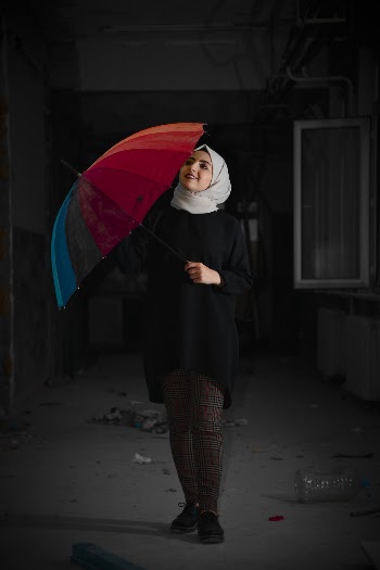 Photo of Smiling Woman in Hijab Holding Umbrella Inside Abandoned Building
