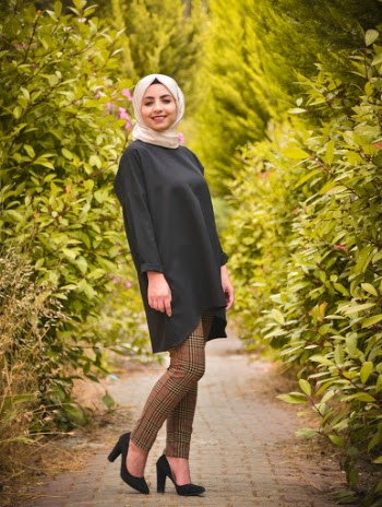Photo of Smiling Woman in Hijab Posing on Footpath In Between Green-leafed Hedge