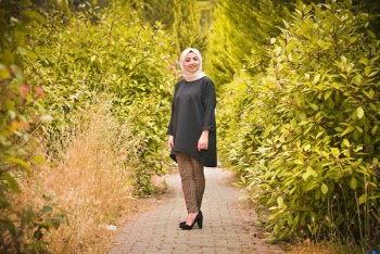 Photo of Smiling Woman in Hijab Posing on Footpath In Between Green-leafed Hedge