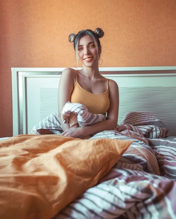 Photo of Smiling Woman in Orange Spaghetti Strap Top Sitting in Bed 
