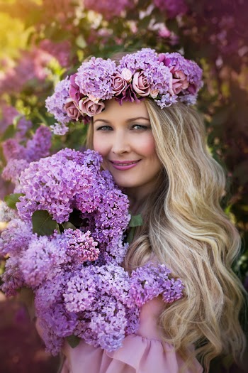 Photo of Smiling Woman in Purple Flower Crown Holding a Bouquet of Purple Flowers