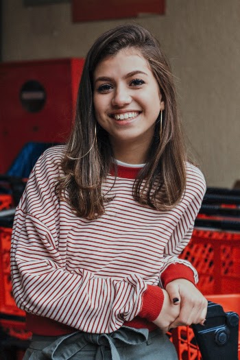 Photo of Smiling Woman in Striped Sweatshirt Standing Next to Shopping cart