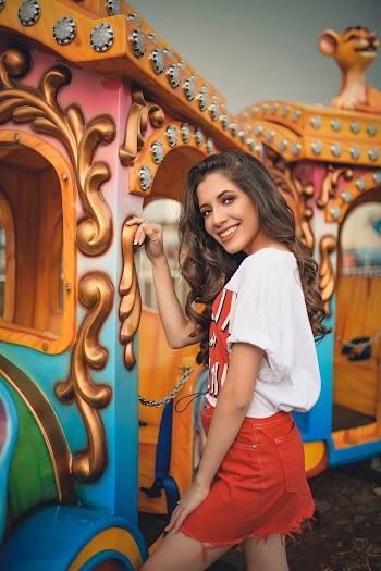 Photo of Smiling Woman in White Shirt and Red Skirt Posing by Train Ride