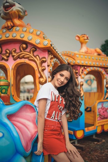 Photo of Smiling Woman in White Shirt and Red Skirt Posing by Train Ride