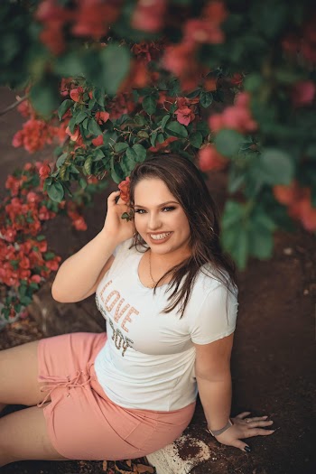 Photo of Smiling Woman in White T-shirt and Pink Skirt Sitting Under Bougainvillea Flowers