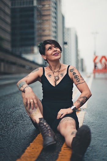 Photo of Smiling Woman Looking up Sitting on Concrete Road 