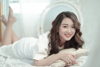 Photo of Smiling Woman Lying Down on a Bed Posing