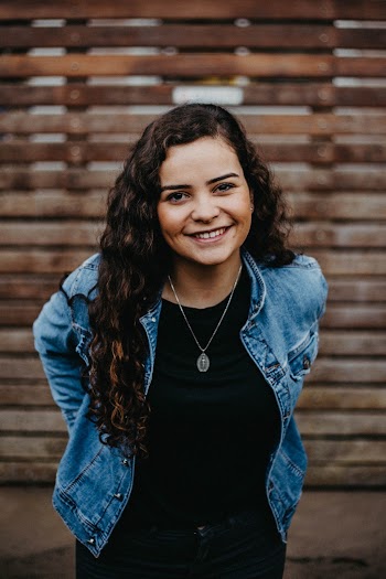 Photo of Smiling Woman Posing with Wooden Fence in the Background