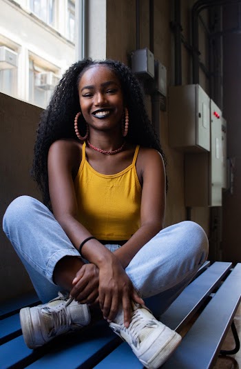 Photo of Smiling Woman Sitting on Bench With Her Legs Crossed