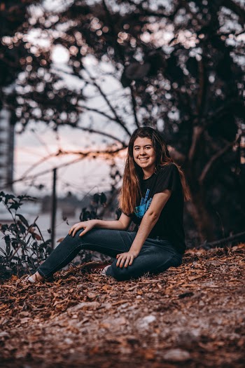 Photo of Smiling Woman Sitting on Ground of Withered Leaves