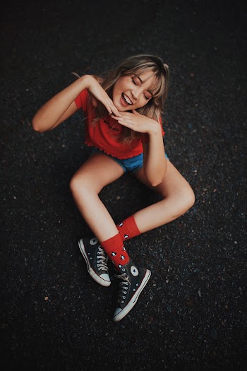 Photo of Smiling Woman Sitting on Ground Posing With Her Eyes Closed