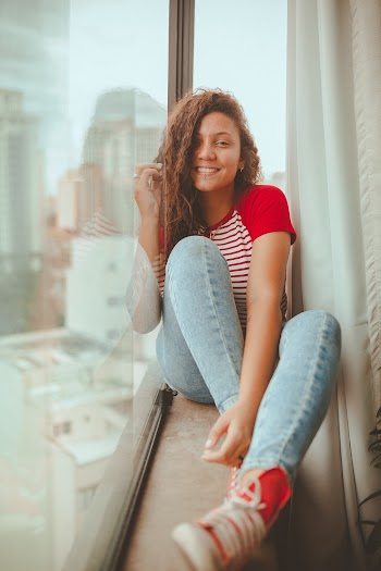 Photo of Smiling Woman Sitting on Window Sill