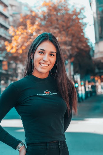 Photo of Smiling Woman Standing Akimbo on Street