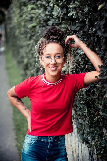 Photo of Smiling Woman Standing Beside Green-leafed Climbing Plant