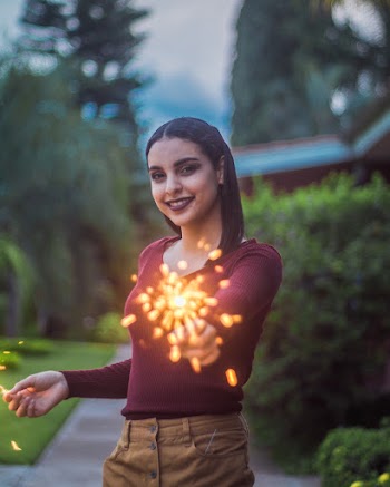 Photo of Smiling Woman Standing while Holding Sparklers
