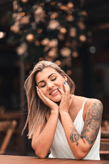 Photo of Smiling Woman with Her Eyes Closed Leaning Her Chin on Her Hands