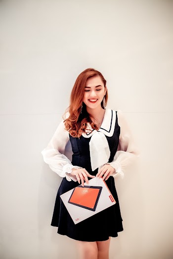 Photo of Smiling Woman With Her Eyes Closed Wearing a Black and White Outfit Standing While Holding a Tablet Box