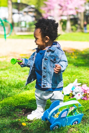 Photo of Standing Baby Boy Holding a Shaker Looking Away