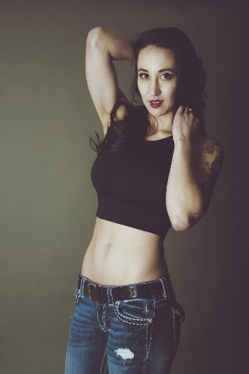 Photo of Standing Woman in Black Crop Top and Blue Jeans Posing In Front of Gray Background