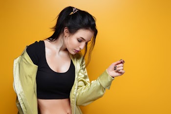 Photo of Standing Woman in Black Crop Top and Yellow Jacket Looking Down