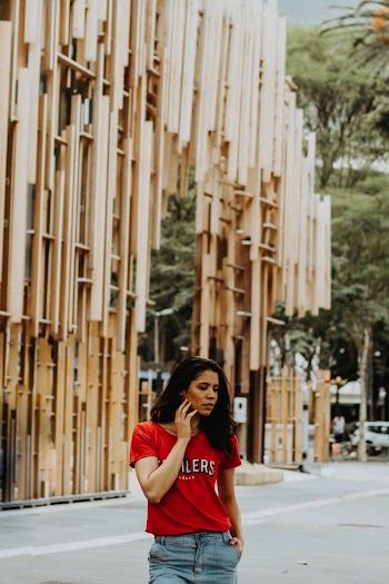 Photo of Standing Woman Posing by the Road With Building in the Background