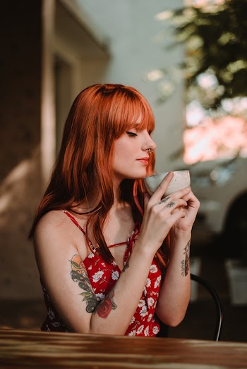 Photo of Tattooed Woman Holding Gray Cup