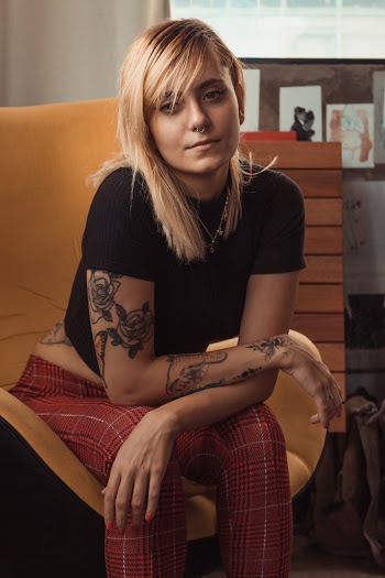Photo of Tattooed Woman Sitting on Suede Sofa Chair