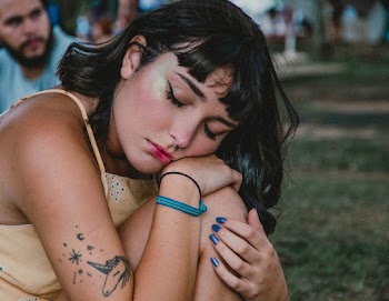 Photo of Tattooed Woman With Her Eyes Closed Resting on Her Knee