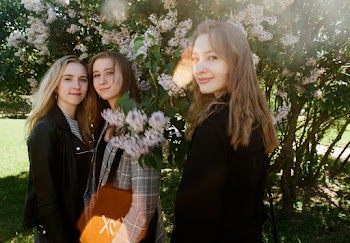 Photo of Three Women Standing Near White Petaled Flowers
